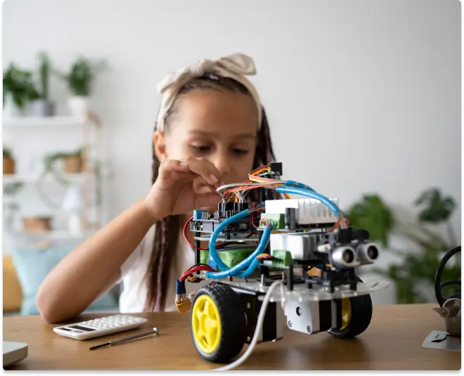 A DIY robot on a table with electronic components visible, in front of a person.