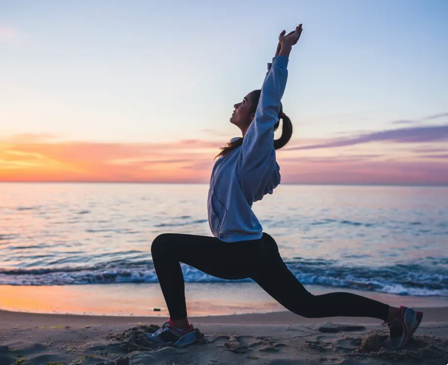 A woman doing yoga on the beach at sunset